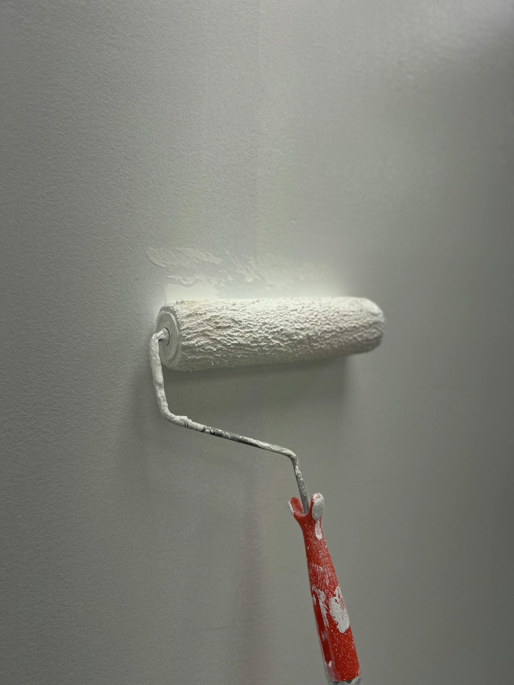 Détail d'application de peinture claire au rouleau sur un mur